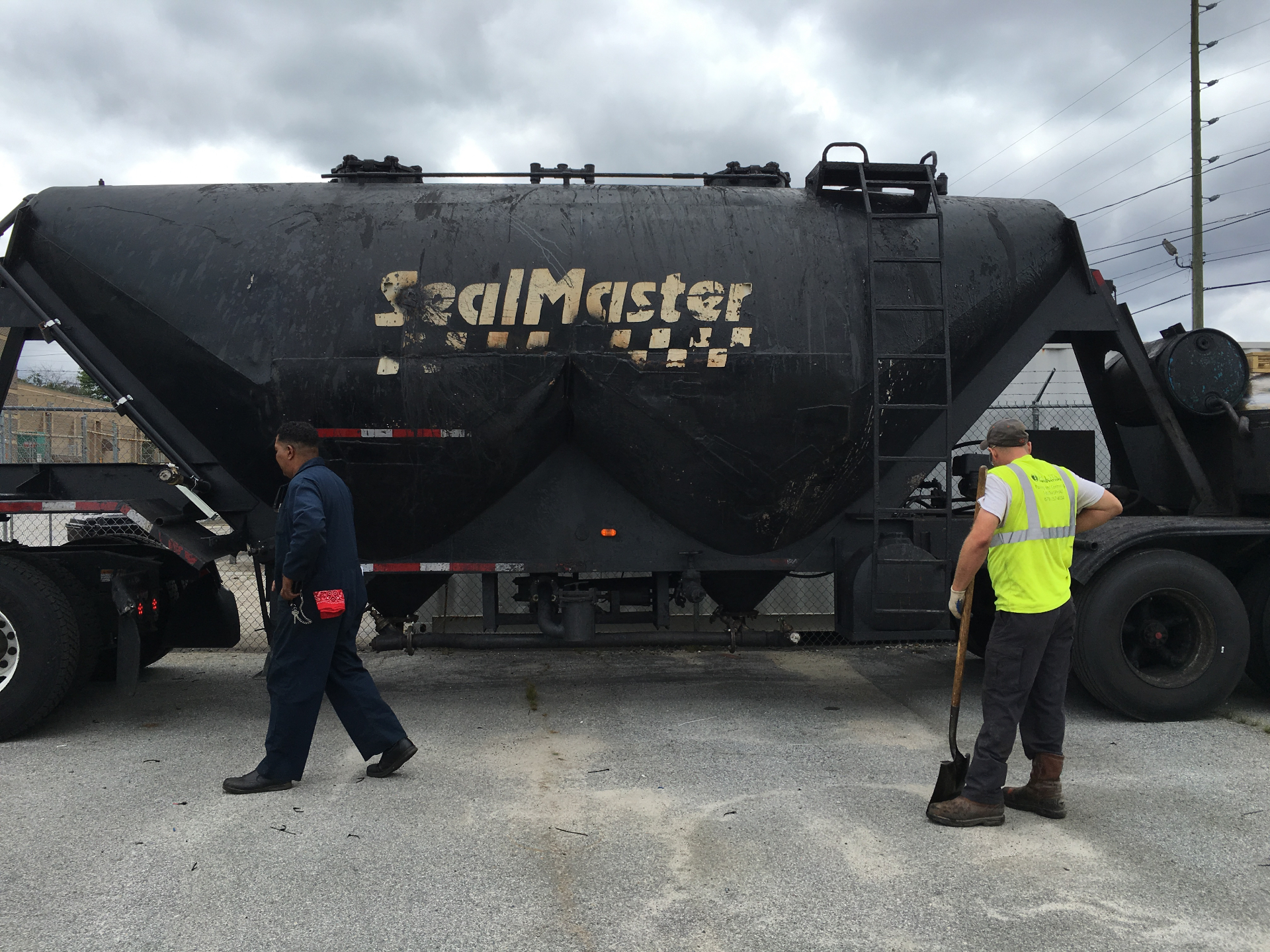 Schell Asphalt & Concrete crew working alongside a SealMaster sealcoating tanker truck