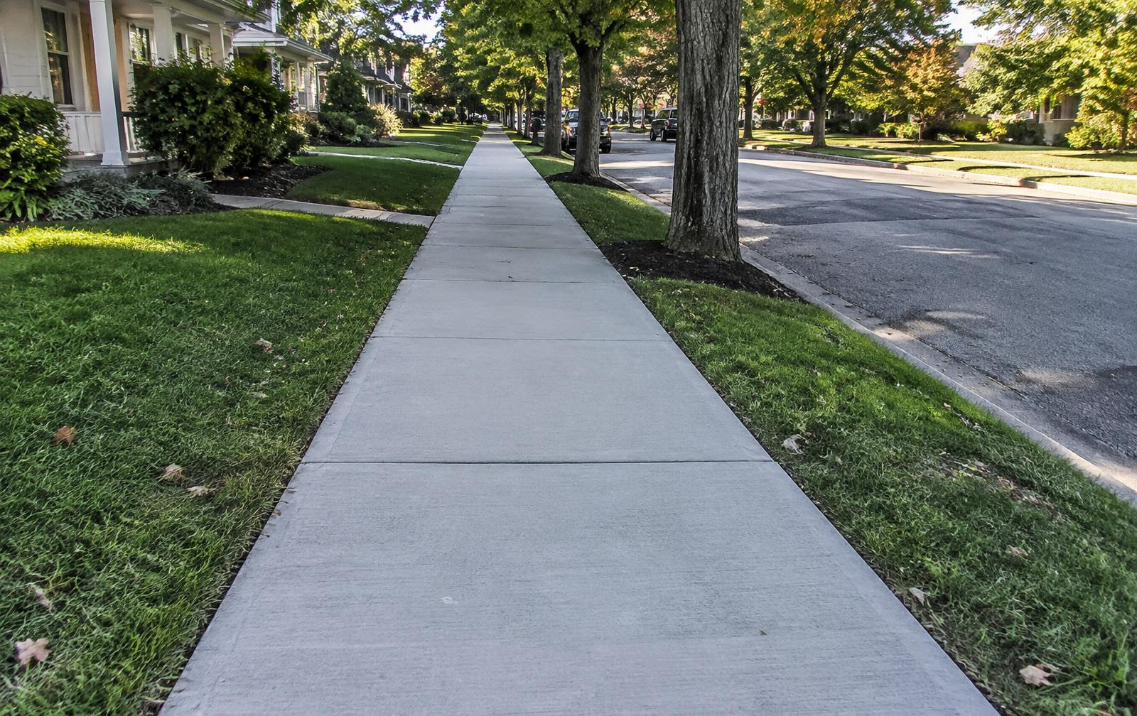 Finished broom-finish concrete sidewalk with clean control joints along a residential street